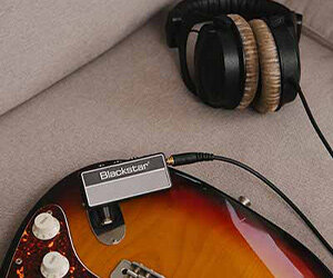 Ampli casque Blackstar amPlug2 FLY branché sur une guitare électrique à côté d'un casque